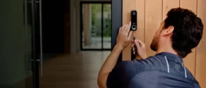 Technician installing a Vivint video doorbell on a wooden exterior wall, ensuring reliable smart home security with professional alarm system installation services.